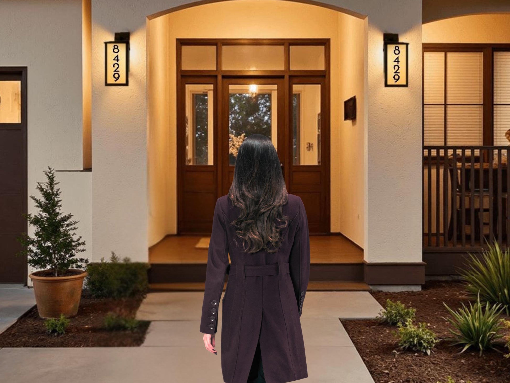 A woman in a purple coat stands in front of a house with a porch, looking away from the camera.