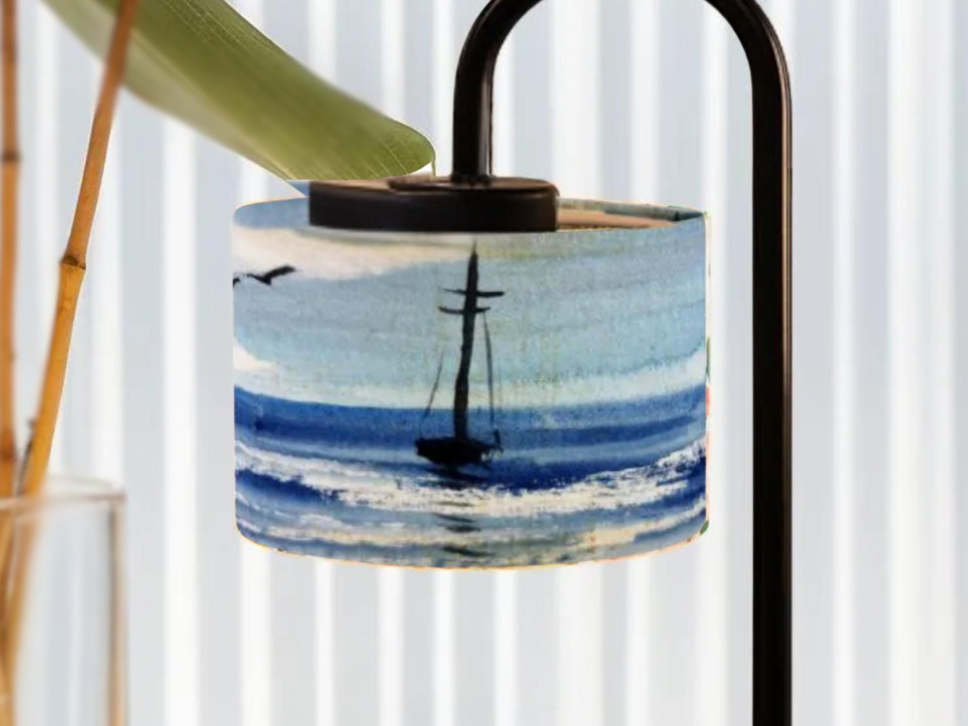 a lamp shade with a painting of a sailboat on the ocean.