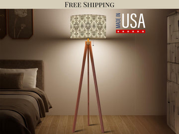 a modern bedroom with a wooden tripod floor lamp, a bed, and a dresser. The lamp has a patterned lampshade and is placed on a wooden stand. The room appears to be well-lit and organized, with a focus on the bed and the lamp.