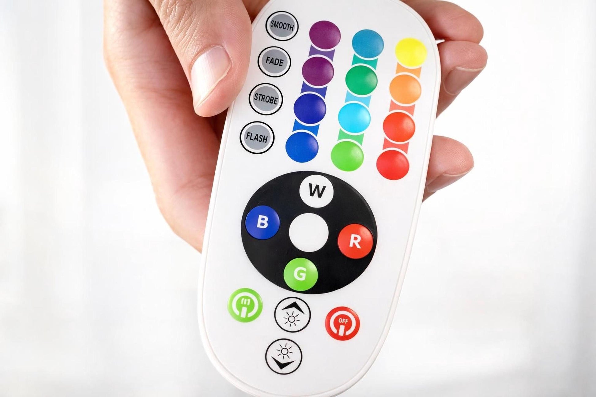 A hand holding a remote control with colorful buttons and symbols on it.